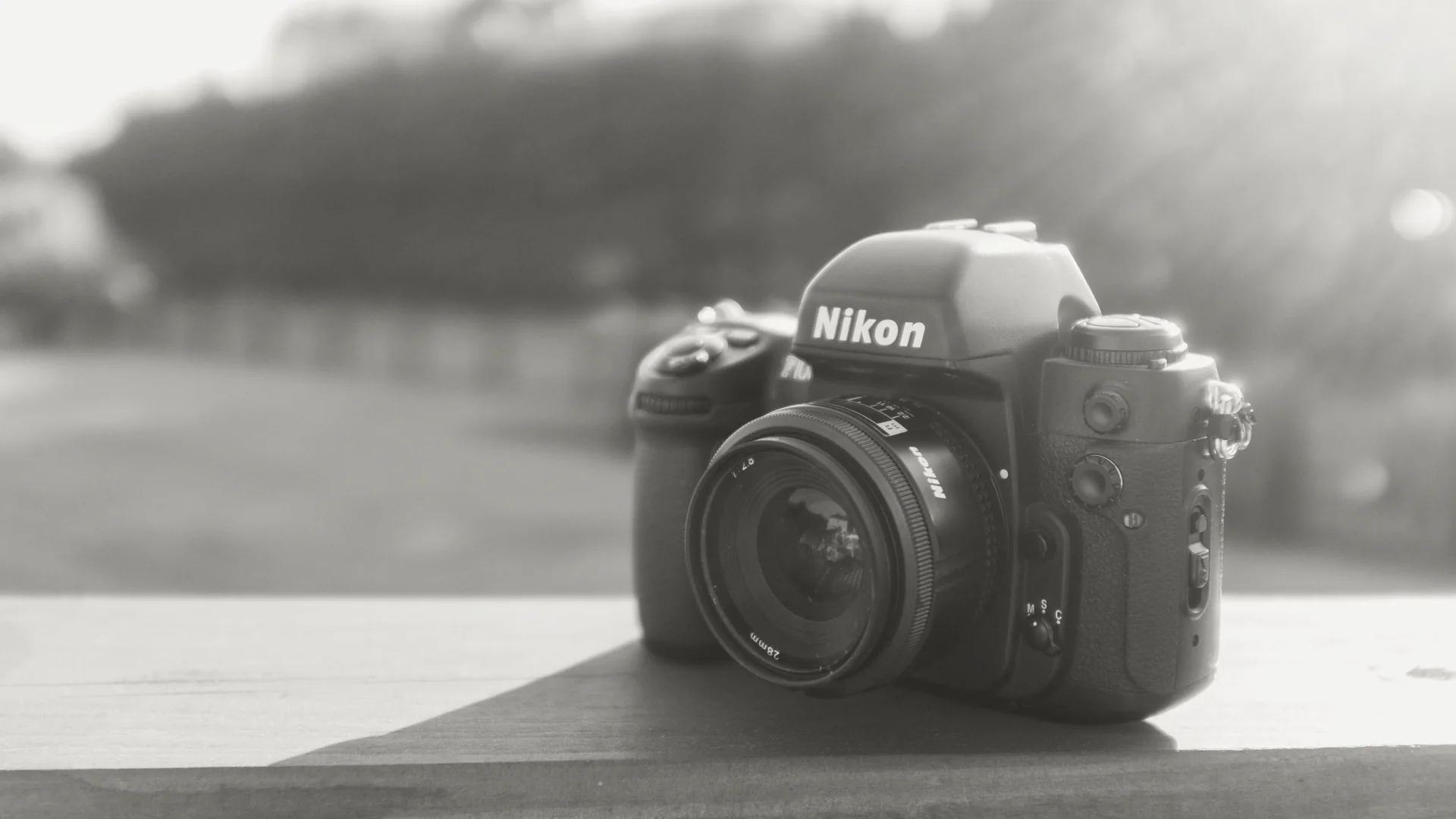 Nikon film camera resting on a sunlit wooden table.