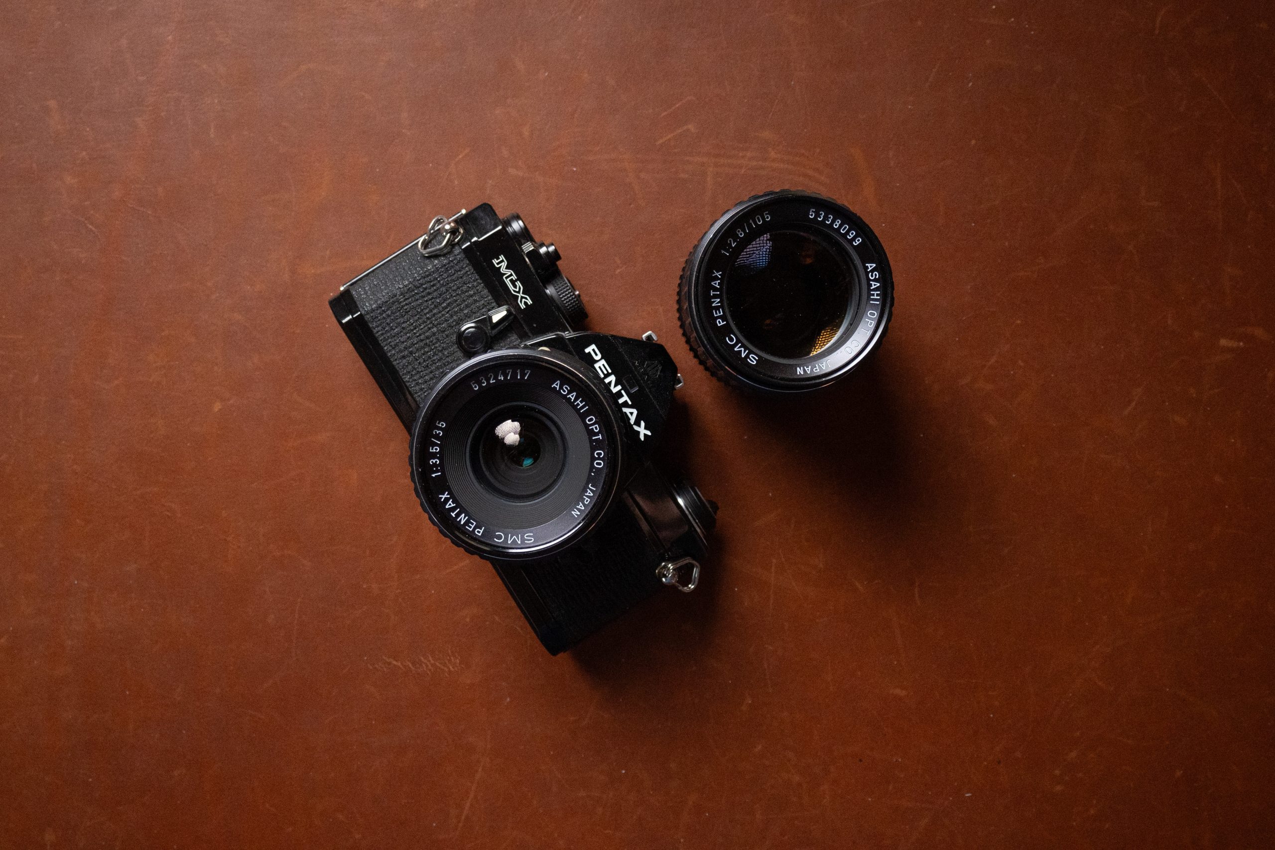 A Pentax MX 35mm film camera with Pentax 35mm 3.5 and 105mm 2.8.