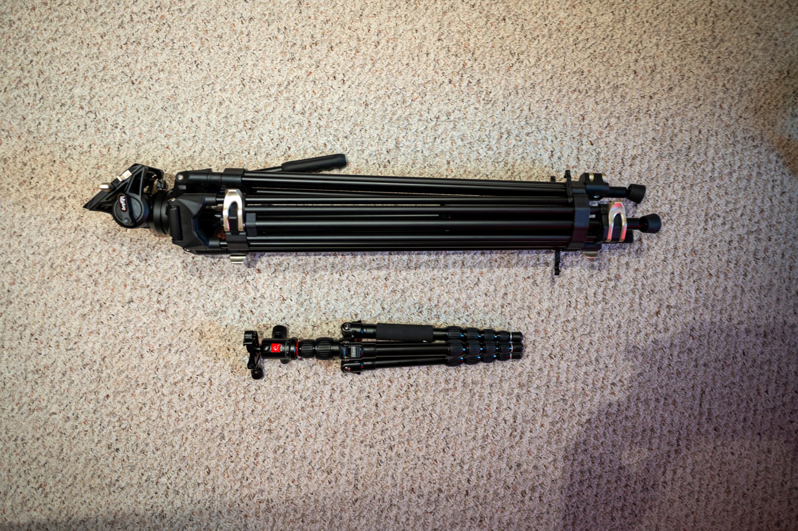 Side-by-side comparison of the folded SmallRig AD-01 tripod and a compact travel tripod, highlighting the AD-01's heavier and bulkier design for stability.