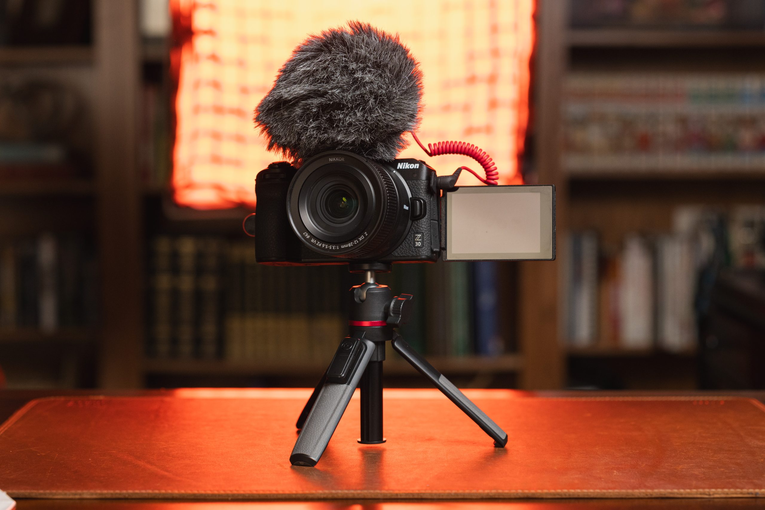 Nikon Z30 camera with Rode VideoMicro microphone on a mini tripod, set up on a desk with a soft orange backlight, ideal for vlogging or content creation.